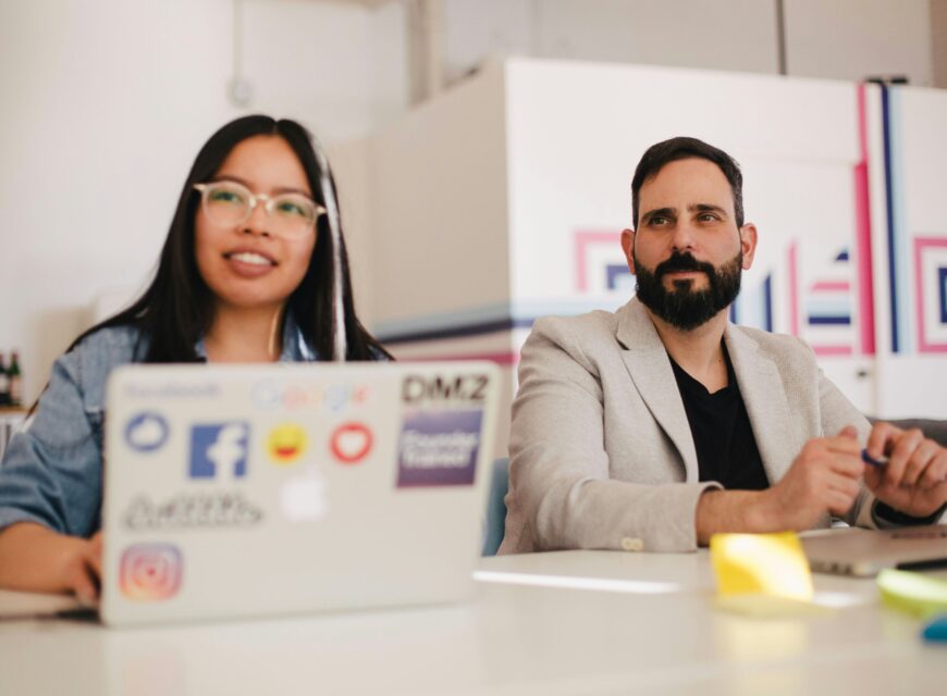 woman and man in office with a Mac laptop
