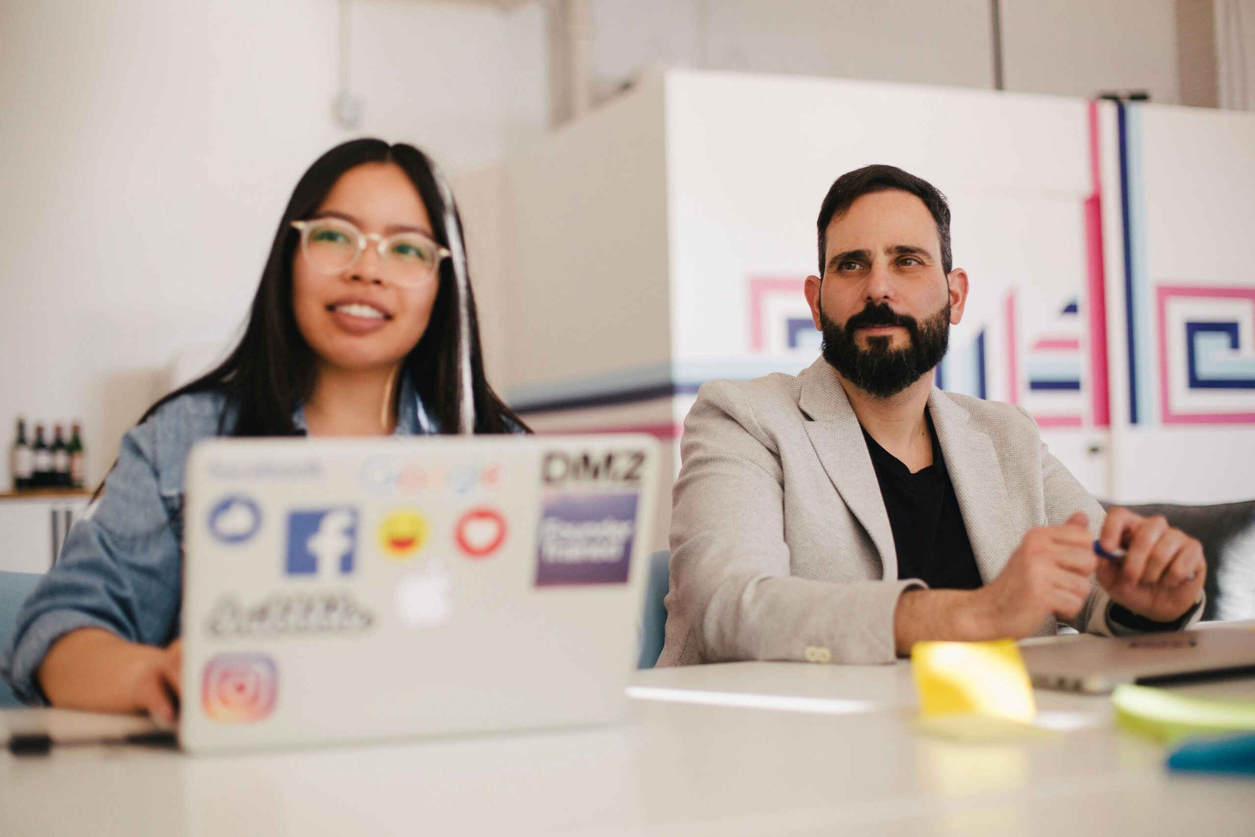 woman and man in office with a Mac laptop