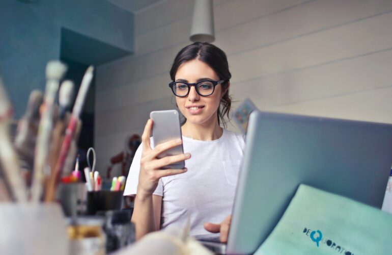 woman in black framed glasses in office on cell phone