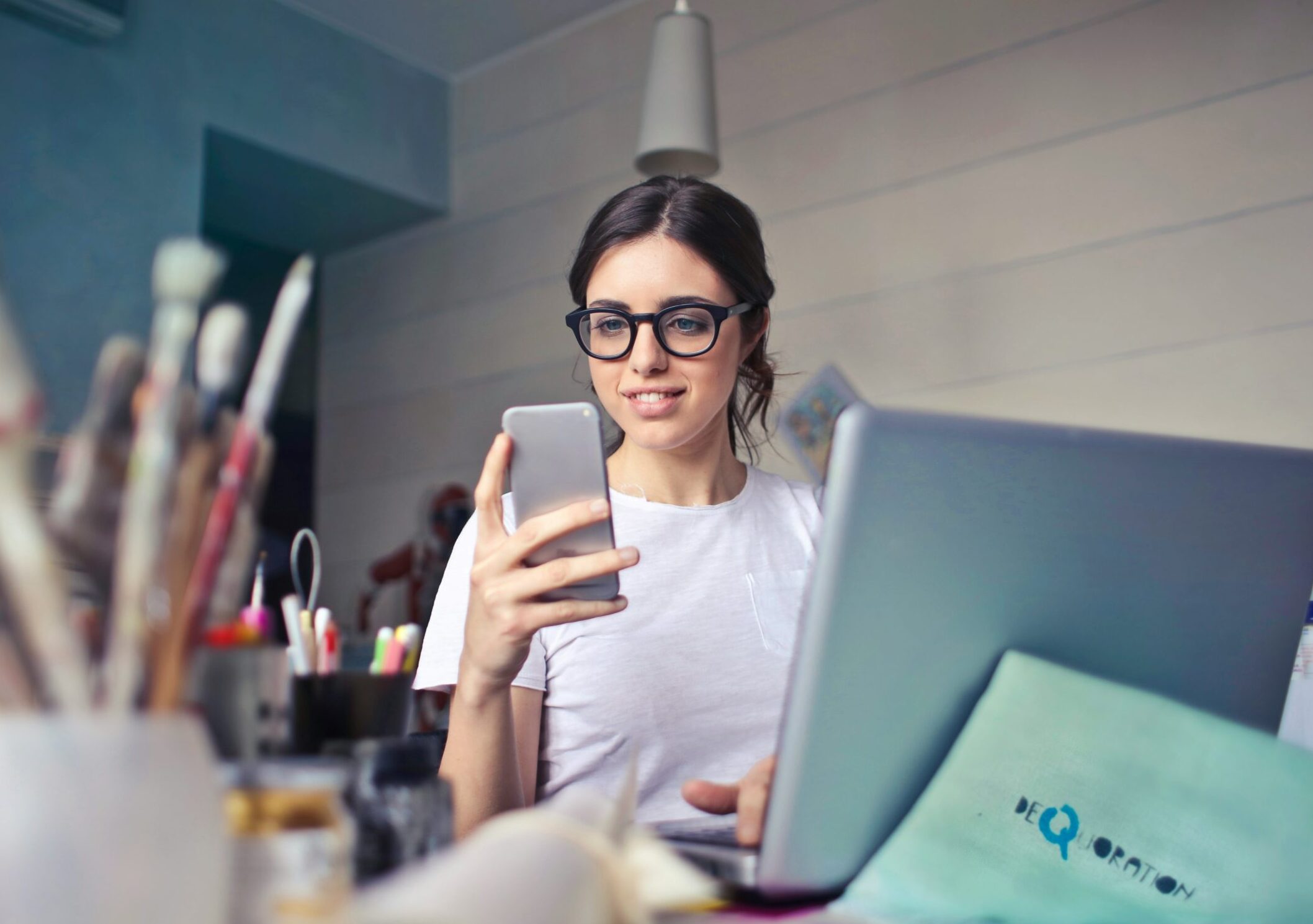 woman in black framed glasses in office on cell phone