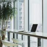 Laptop on an office bench overlooking the windows with a plant