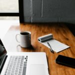 Laptop, coffee mug and notepad on a wooden desk