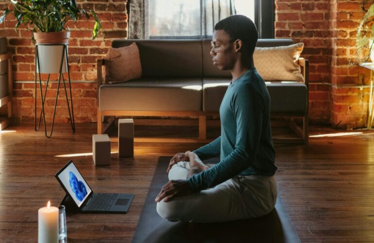Man sitting cross legged on yoga mat in meditation