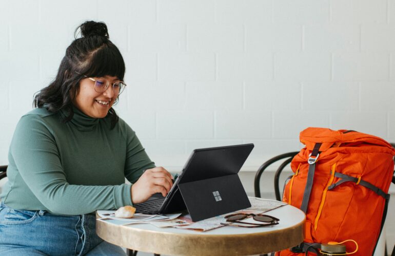 woman working on a laptop with a red duffell bag