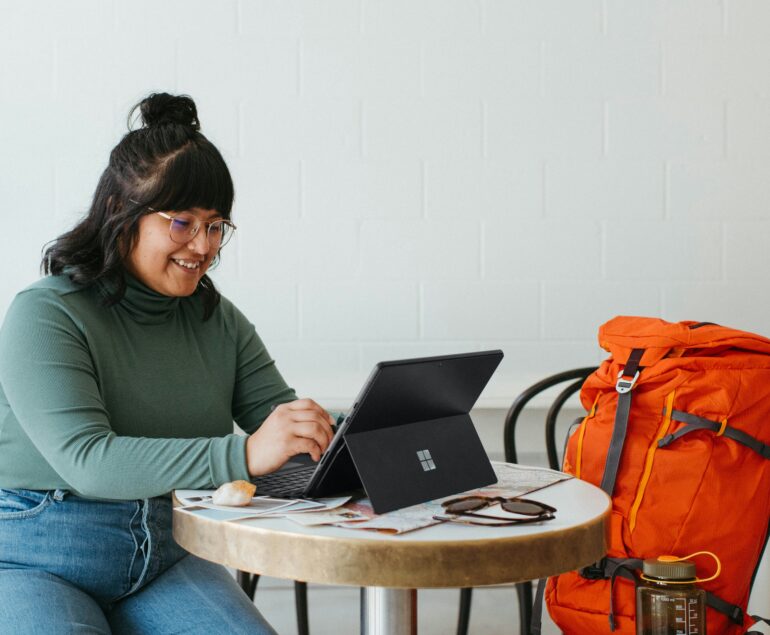woman working on a laptop with a red duffell bag