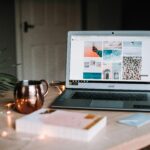 Mac laptop on a table with a gold coffee mug